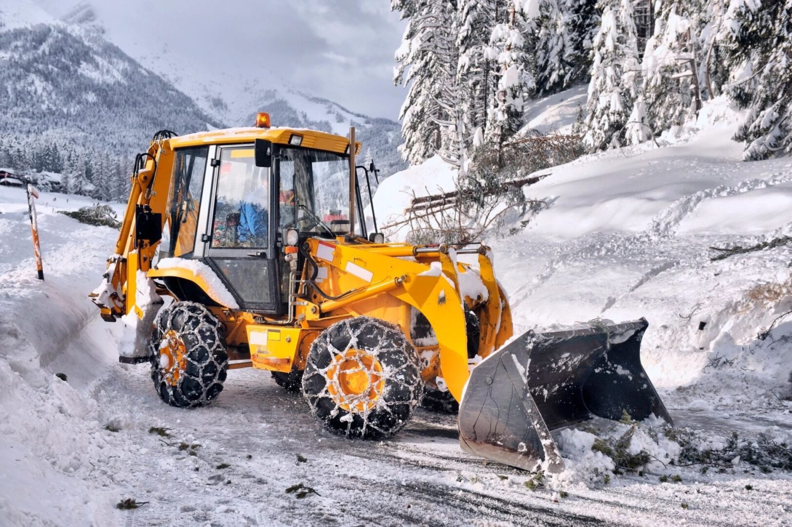 A yellow tractor with snow on it's back