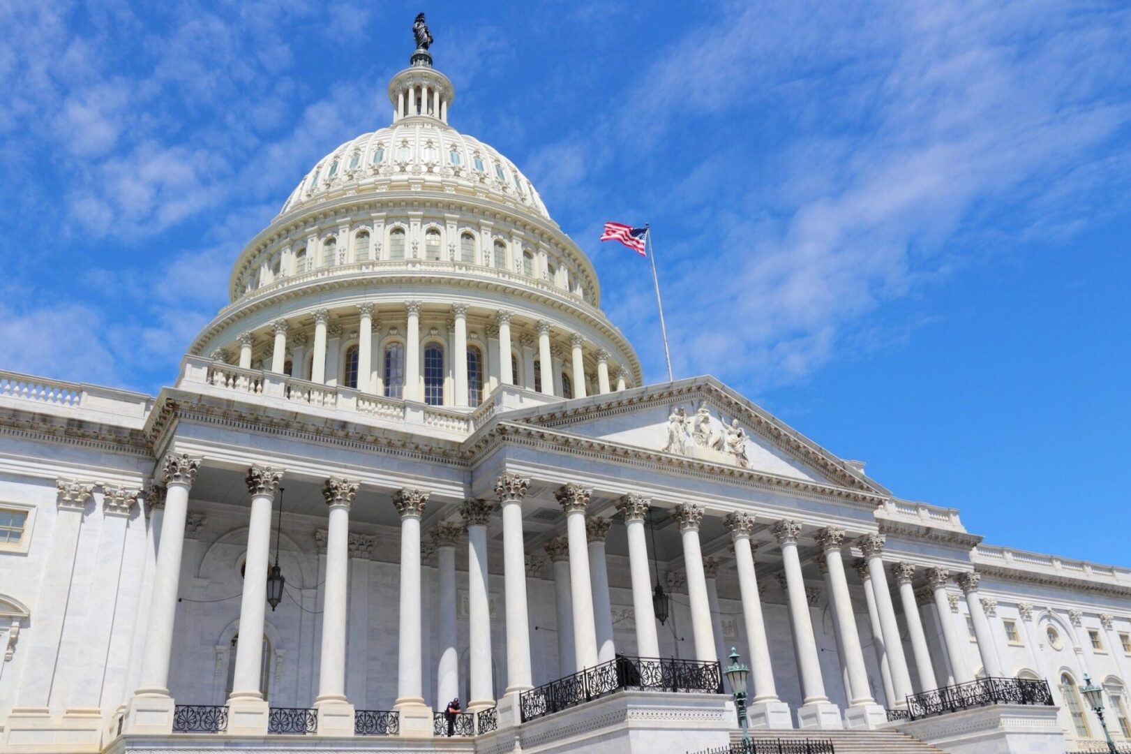 A large white building with columns and a flag on top.