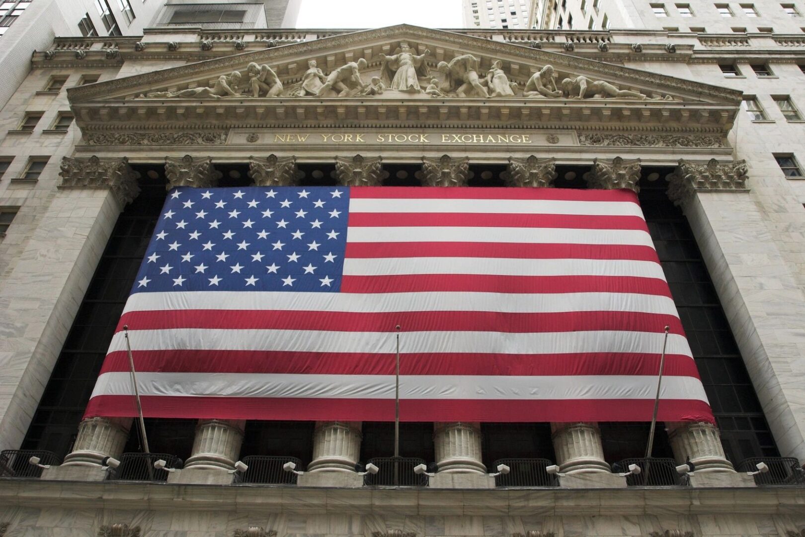 A large american flag hanging from the side of a building.