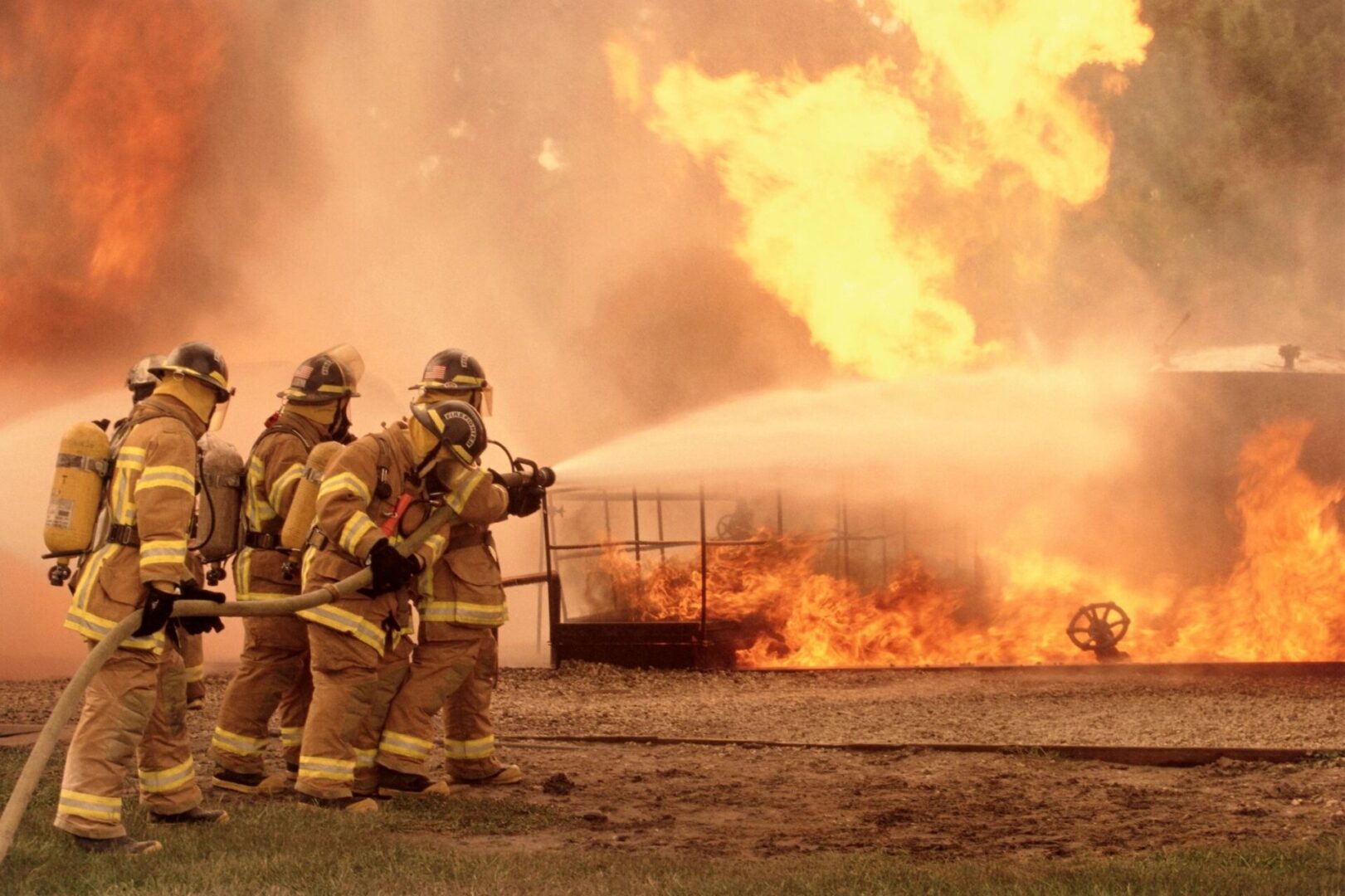 A group of firefighters standing next to a fire.