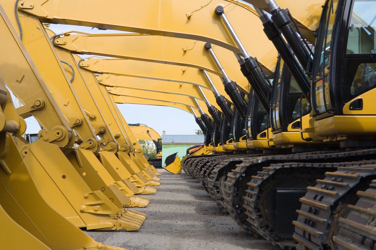 A row of yellow construction equipment parked in a lot.