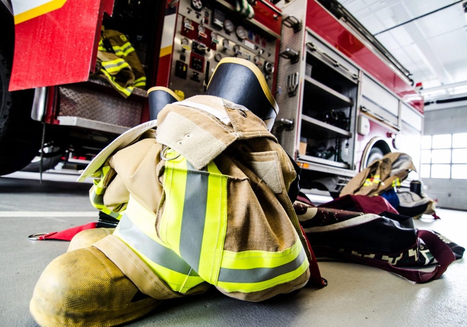 A fireman laying on the ground next to a fire truck.